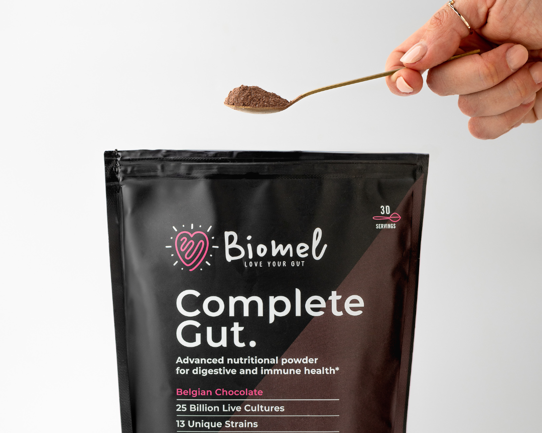 Women holding a serving spoon of Biomel Belgian Chocolate Complete Gut.